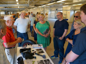 Personer som står runt ett bord när männen från Gislaveds industrimuseum talar om gummi