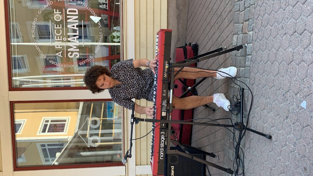 Robert Hoban spelar piano och sjunger utanför turistbyrån